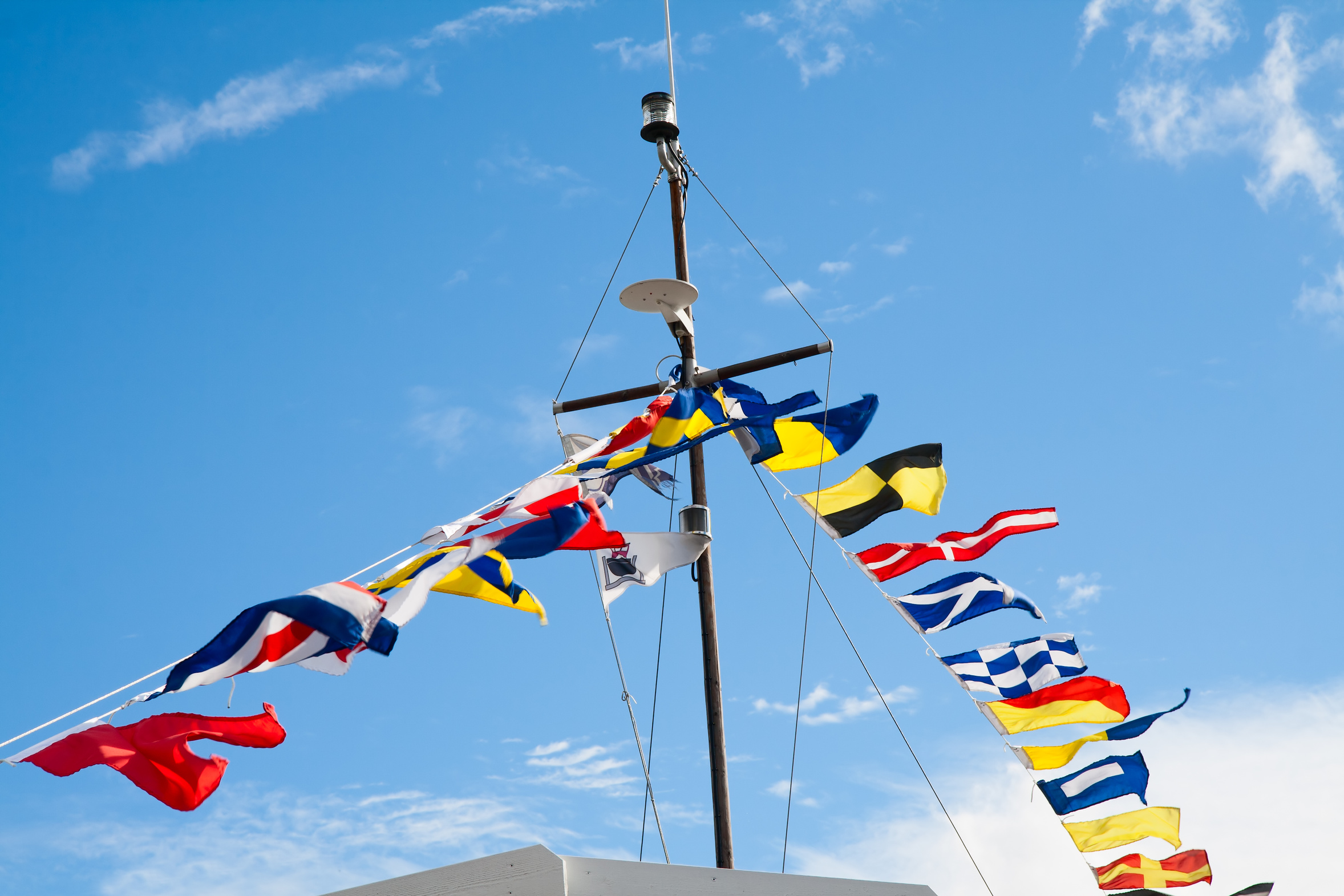 Mast with signal flags against blue sky